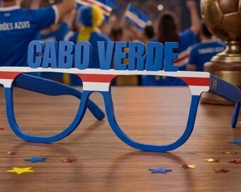 May include: Blue plastic novelty glasses featuring the text CABO VERDE in large blue letters across the top frame. The frame is decorated with horizontal red, white, and blue stripes, matching the colors of the Cape Verdean national flag.