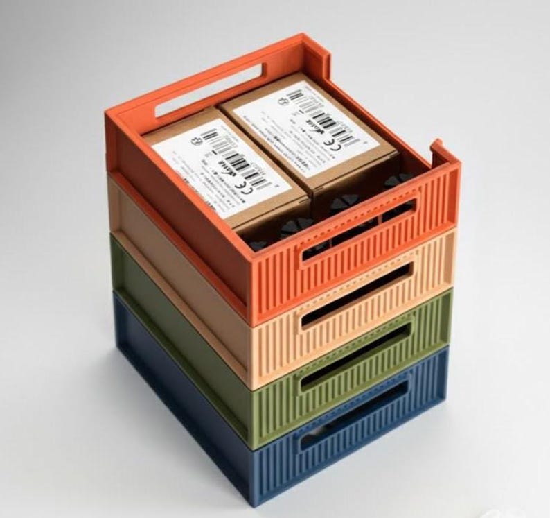 3D printed stackable storage bins in various colors including orange, green, and blue. A vertical modular organizer showing the interlocking system for a desk or workshop setup.
