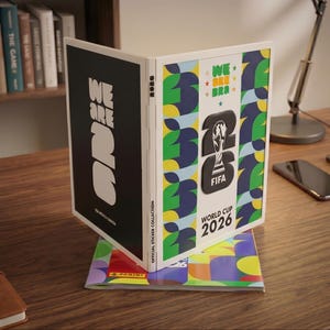 May include: A Panini official sticker collection album for the FIFA World Cup 2026. The album features a black cover with white text reading WE ARE 26 and a white cover with green, yellow, and blue patterns, the FIFA trophy logo, and text.