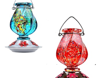 Könnte beinhalten: Zwei Glas-Kolibri-Futterspender mit einem wirbelnden, farbenfrohen Design. Der Futterspender links ist blau mit gelben und roten Akzenten. Der Futterspender rechts ist rot mit gelben und blauen Akzenten. Beide Futterspender haben einen Metallhaken und einen Sockel mit einem Blumendesign.