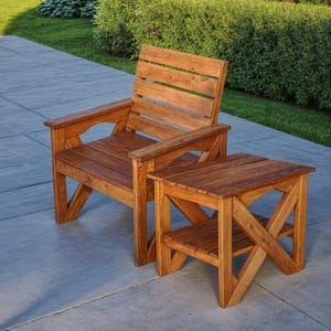 Puede incluir: Una silla y una mesa auxiliar a juego de madera con acabado en madera natural. La silla tiene un respaldo de listones y un asiento ancho. La mesa tiene un solo estante.