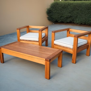 May include: A wooden outdoor furniture set with two chairs and a coffee table. The chairs have white cushions and the table has a natural wood finish.