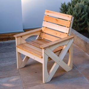 May include: A wooden chair with a light brown finish and a natural wood grain. The chair has a slatted back and a curved seat. The chair is made of solid wood and has a sturdy construction.