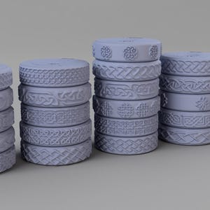 May include: A collection of twenty-three light grey circular rings arranged in five vertical stacks. Each ring features a distinct embossed Celtic knotwork pattern around its outer edge, showcasing various intricate braided and geometric designs.