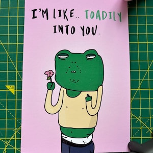 Tarjeta genial de sapo hipster para tu pareja. Aniversario o cualquier ocasión. Impresa en cartulina mate premium de 300 g/m². Diseño con un toque de humor. Pegatina gratis.