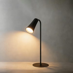 May include: A modern black desk lamp with a conical shade and a curved arm. The lamp has a circular base and emits a warm, inviting light. The lamp's height is approximately 18 inches.
