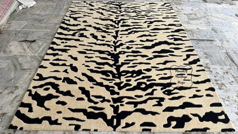 May include: A rectangular area rug featuring a high-contrast tiger stripe pattern in black and beige. The design consists of irregular, horizontal black stripes across a solid beige background. A small label reads House Of Heritage Rugs.