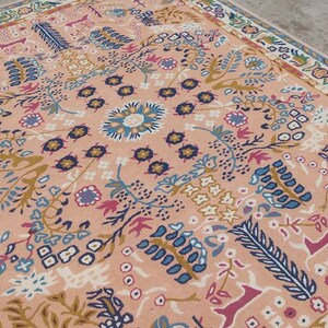 Peut inclure: Tapis rectangulaire &agrave; motifs floraux dans les tons p&ecirc;che, bleu et cr&egrave;me. Le tapis pr&eacute;sente un motif de m&eacute;daillon central entour&eacute; de fleurs et de feuilles stylis&eacute;es. La bordure pr&eacute;sente un motif floral r&eacute;p&eacute;titif.