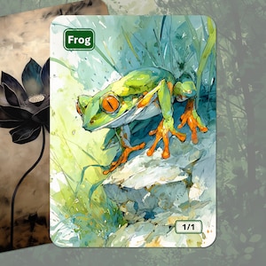 May include: A watercolor-style illustration of a green frog with orange feet and eyes, labeled "Frog." The frog is perched on a rock amidst green foliage. A second card shows a black lotus flower. The cards have a fantasy theme.