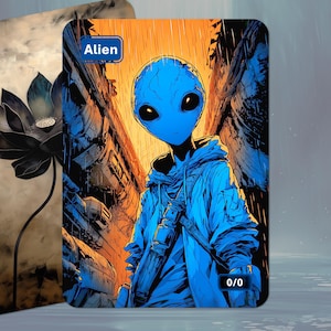 May include: A blue alien character with large black eyes, wearing a blue hoodie, stands in a city scene. The card is labelled "Alien" in a blue box. A second card with a black and white flower is in the background.