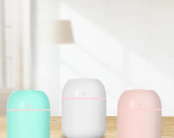 May include: Three small, round, ultrasonic humidifiers. The humidifiers are white, light blue, and light pink. They have a small opening on the top for adding water and essential oils.
