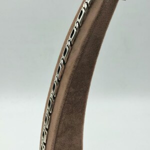 May include: A silver chain bracelet with a box chain design. The bracelet is displayed on a brown velvet stand.