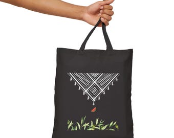 May include: Black tote bag with a white geometric design, a slice of watermelon, and green foliage. The bag is held by a person. The tote bag has two black handles.