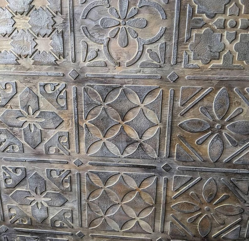 May include: Close-up of a wooden surface with a repeating pattern of carved floral and geometric designs. The designs are in a lighter color than the wood, creating a contrast. The wood has a natural, aged appearance.