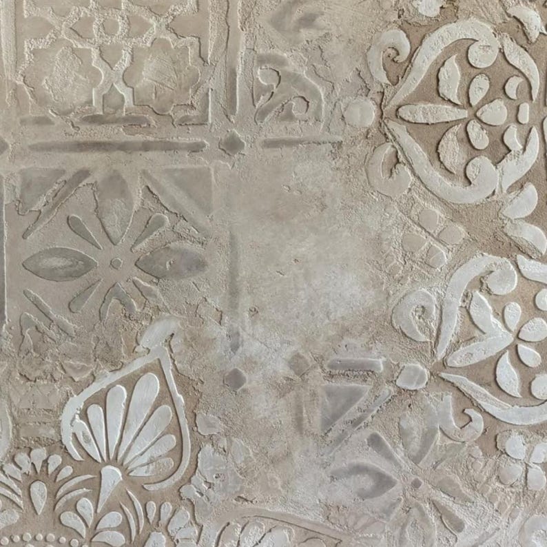 May include: Close-up of a textured, beige surface with a repeating pattern of raised white floral and geometric designs. The design elements include stylized flowers, leaves, and geometric shapes, creating a decorative, vintage aesthetic.