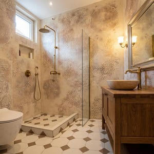 May include: A bathroom with a vintage design. The walls have a textured, patterned design in beige and gold tones. A wooden vanity with a stone sink and brass fixtures complements the shower and toilet. The floor has a geometric tile pattern.