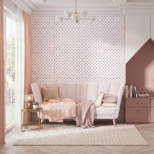 May include: A pink velvet sofa with a matching throw blanket and pillows. The room features a patterned wallpaper, a gold side table with a lamp, and a neutral rug. A chandelier hangs from the ceiling.