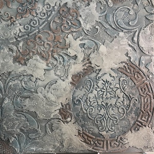 May include: Textured square artwork with a distressed, layered appearance. The piece features a mix of gray, white, and bronze tones, with ornate, embossed floral and geometric patterns. The design has a vintage, weathered aesthetic.