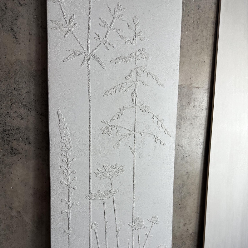 Peut inclure: Une &oelig;uvre d'art murale rectangulaire, blanc cass&eacute;, avec un motif botanique en relief. L'&oelig;uvre repr&eacute;sente diverses plantes, notamment de hautes tiges avec des feuilles et des fleurs. Le relief cr&eacute;e un effet textur&eacute; en trois dimensions.