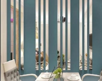 May include: A teal-colored room divider with vertical slats, creating a modern aesthetic. The divider separates a dining area with a white table, chairs, and a glass centerpiece. The design allows light to pass through, enhancing the room's openness.