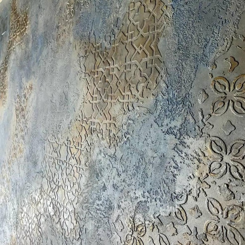 May include: Textured wall art with a distressed, aged appearance. The surface features a mix of gray, blue, and beige tones with embossed geometric and floral patterns. The design creates a sense of depth and visual interest.
