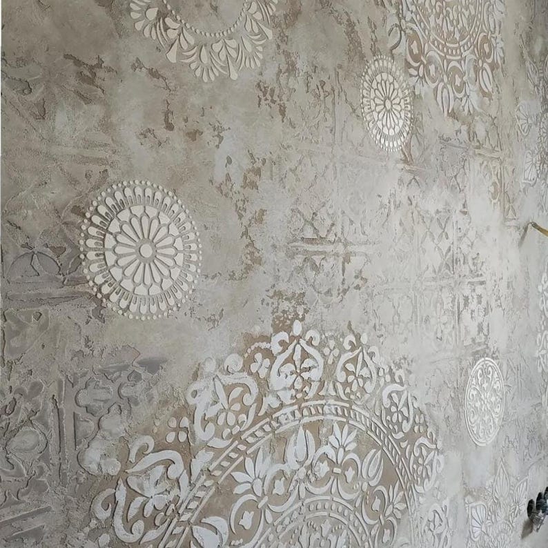 May include: Textured wall with a distressed, aged appearance. The wall features a neutral color palette with white, raised, circular and floral patterns. The design creates a vintage, artistic aesthetic, suitable for interior decor.