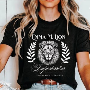 A woman wearing a black t-shirt with a lion graphic and text printed on it.