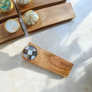 Pu&ograve; includere: Un set di quattro fermaporte in legno con intarsi di conchiglie diversi. I fermaporte sono realizzati in legno naturale e hanno una finitura liscia. Gli intarsi di conchiglie sono in vari motivi e colori.