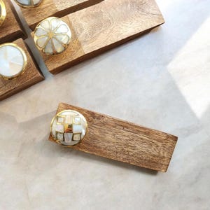Pu&ograve; includere: Set di quattro fermaporte in legno con pomelli rotondi decorativi con intarsi in conchiglia bianca e dorata. I pomelli hanno motivi diversi.