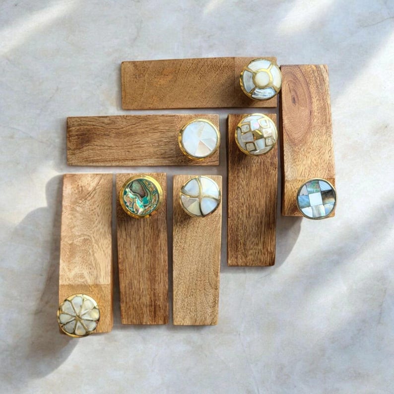Pu&ograve; includere: Sette blocchi rettangolari in legno con pomelli decorativi in conchiglia e oro. I pomelli sono di vari motivi e colori, tra cui bianco, verde e blu.