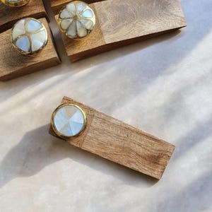 Pu&ograve; includere: Un set di quattro tiretti per cassetti in legno con intarsi in madreperla bianca e dorata. I tiretti sono disposti su una superficie in legno.