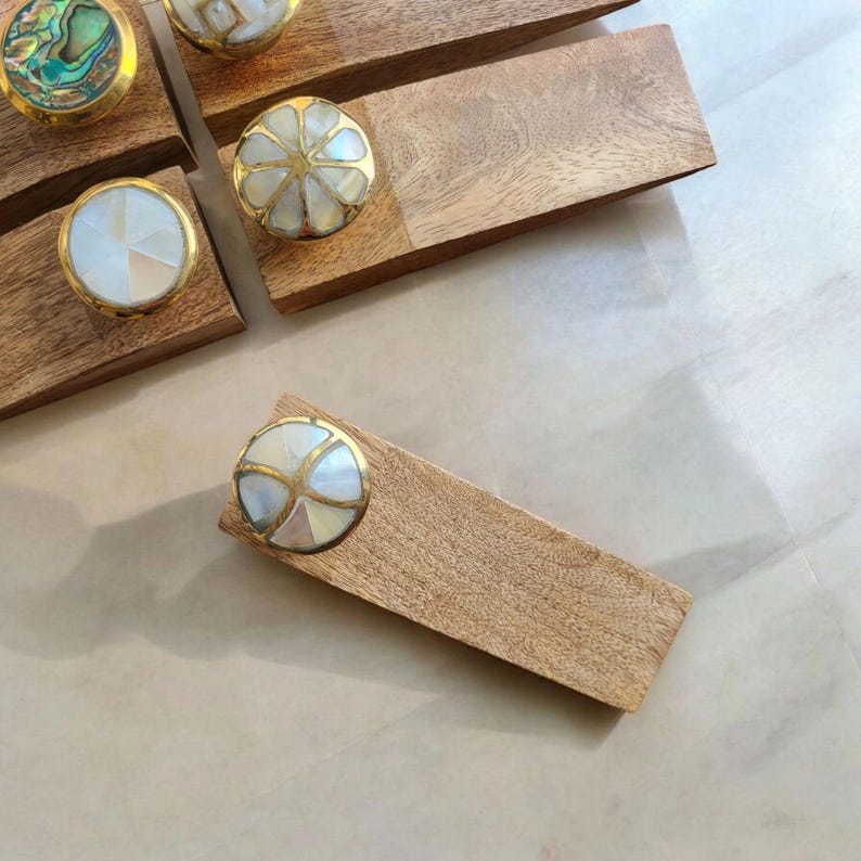 Pu&ograve; includere: Set di cinque fermaporta in legno con pomelli decorativi rotondi in conchiglia e ottone. I fermaporta sono in varie tonalit&agrave; di legno marrone.
