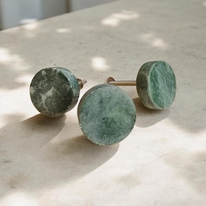 May include: Three round green marble cabinet knobs with a silver metal screw. The knobs have a mottled green and white pattern.