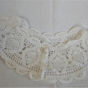 May include: White crocheted lace collar with a button closure.