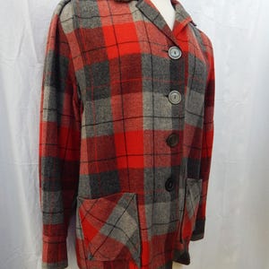May include: A red, gray, and black plaid jacket with a collared neckline and three buttons. The jacket has two front pockets and long sleeves. The fabric appears to be a wool blend.