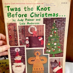 May include: A vintage craft instruction book titled "'Twas the Knot Before Christmas..." by Judy Palmer and Lois Anderson. The cover features various Christmas-themed macrame projects, including a tree, Santa, and an angel.