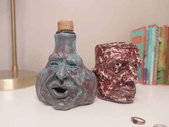 A hand-sculpted gothic bottle with a creepy cork face — part apothecary oddity, part desk art, all "what IS that?" energy.