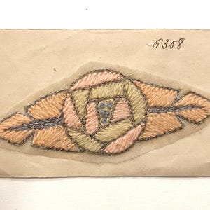May include: Embroidered textile patch featuring a central rose design in shades of peach, yellow, and pink, with silver-colored thread accents. The patch is mounted on a beige paper backing, with the number "6358" handwritten in black ink.
