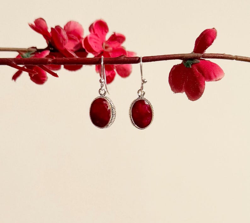 Op de afbeelding: Een paar zilveren oorbellen met ovale rode edelsteen druppels.