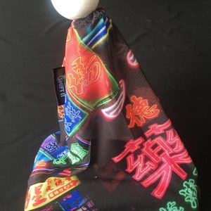 May include: A black mesh gear shift knob cover with a neon sign design featuring Japanese characters. The cover has a white ball on top.
