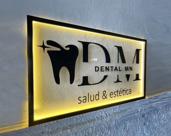 May include: A black and white sign with a glowing yellow border. The sign says "DM Dental MN salud & estética". A stylized tooth with a star is in the upper left corner.