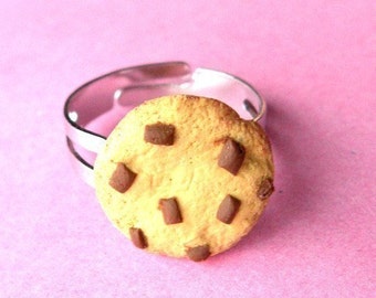 May include: A silver ring with a chocolate chip cookie charm. The cookie is made of polymer clay and has a realistic appearance.