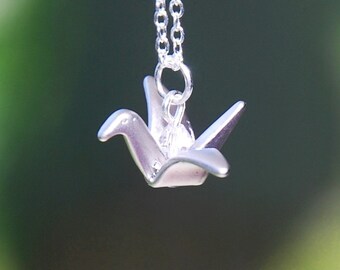 May include: A silver origami crane pendant necklace. The crane is a symbol of peace and good luck.