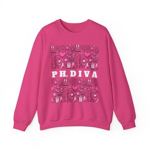Peut inclure: Un sweat-shirt rose vif à manches longues. Le devant présente un motif de graphiques scientifiques roses et blancs, notamment des cœurs, des béchers et des brins d'ADN. Les mots "P.H. DIVA" sont imprimés en lettres blanches.