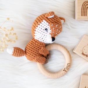 May include: A crocheted fox toy with a wooden ring attached. The ring has the name "Finn" engraved on it.