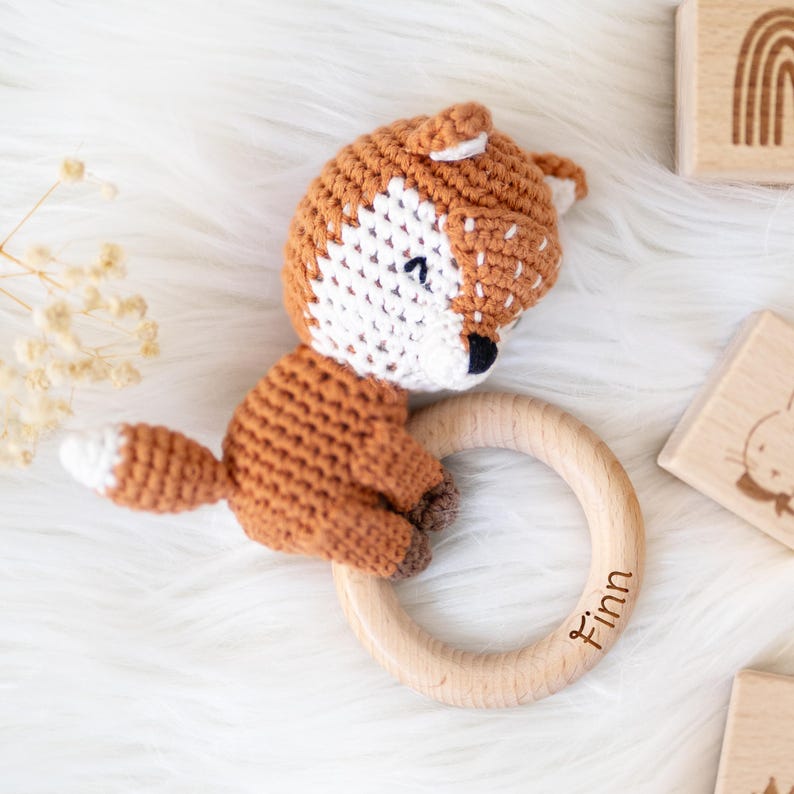 May include: A crocheted fox toy with a wooden ring attached. The ring has the name "Finn" engraved on it.