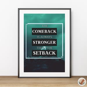 Könnte beinhalten: Gerahmter Kunstdruck mit dem Zitat "THE COMEBACK IS ALWAYS STRONGER THAN THE SETBACK" in weißem Text auf einem türkis-schwarzen Hintergrund. Der Druck befindet sich in einem schwarzen Rahmen und wird auf einer Holzoberfläche angezeigt.