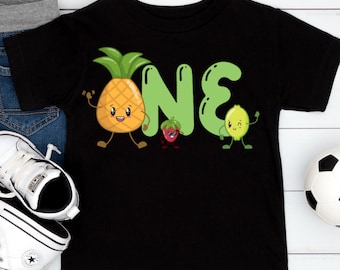 May include: Black toddler t-shirt with a colorful graphic. The graphic features the word "ONE" with a pineapple, strawberry, and lime as the letters. The pineapple, strawberry, and lime have cartoon faces and arms and legs.