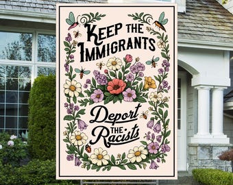 May include: A yard sign with the text "Keep the Immigrants, Deport the Racists" in a floral design. The sign is cream-colored with a black border and is displayed on a metal stand in a front yard.