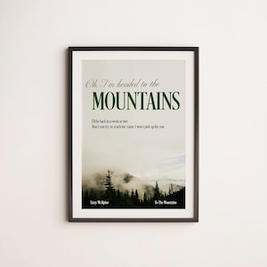 Peut inclure: Une impression encadrée avec un texte superposé vert et blanc sur une photo d'une chaîne de montagnes avec des arbres. Le texte dit "Oh, I'm headed to the MOUNTAINS I'll be back in a week or two Don't you try to reach me 'cause I won't pick up for you" et est attribué à "Lizzy McAlpine" et "To The Mountains".